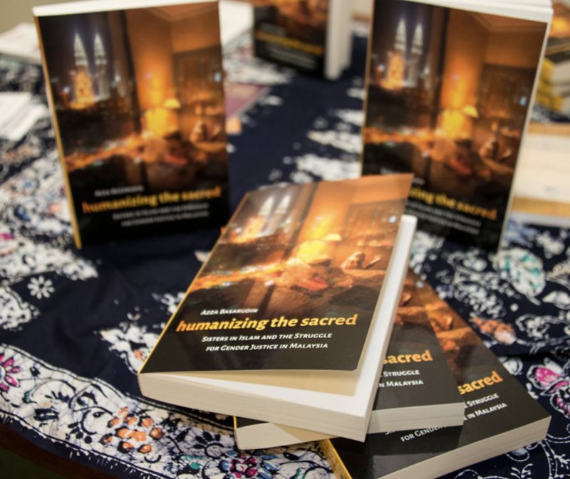 Copies of Humanizing the Sacred displayed on batik cloth at a book launch