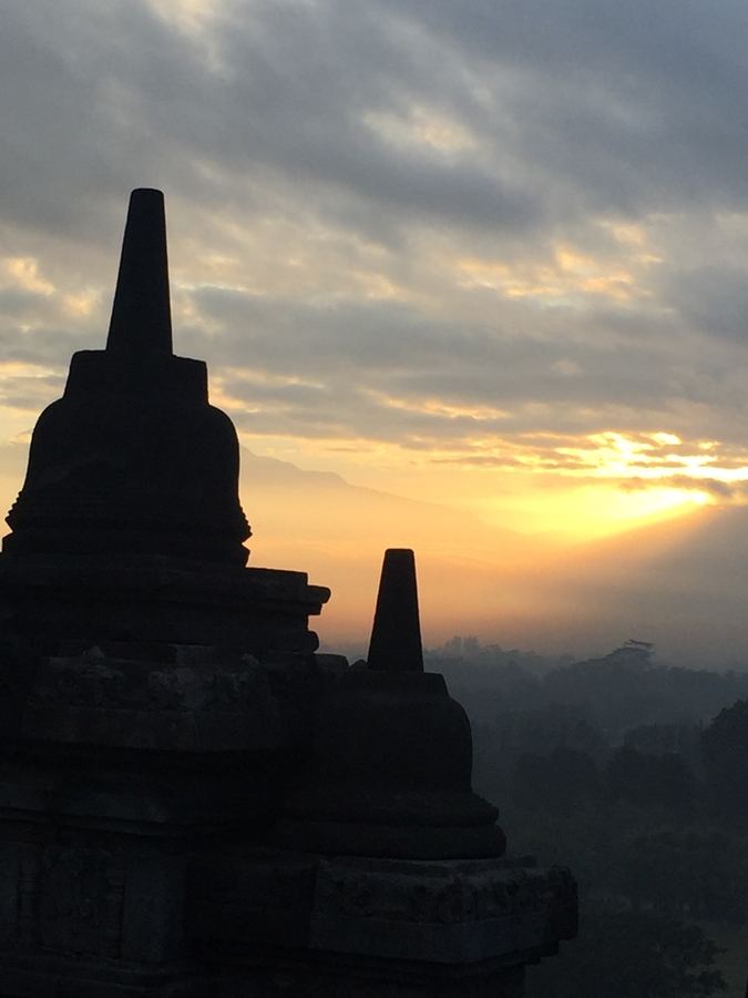 Stupas at Borobudur silhouetted against a hazy sunrise