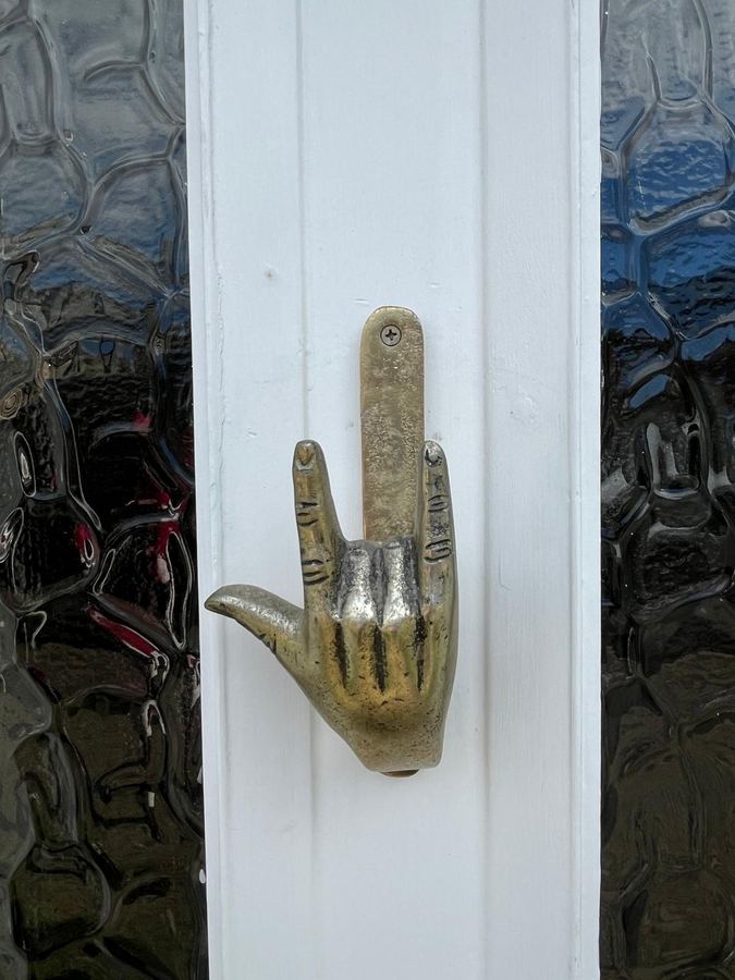 A brass hand-shaped door knocker on a white panelled door