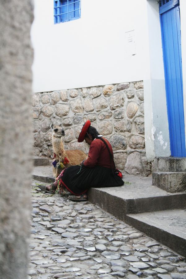 A woman seated on cobbled steps beside a blue doorway
