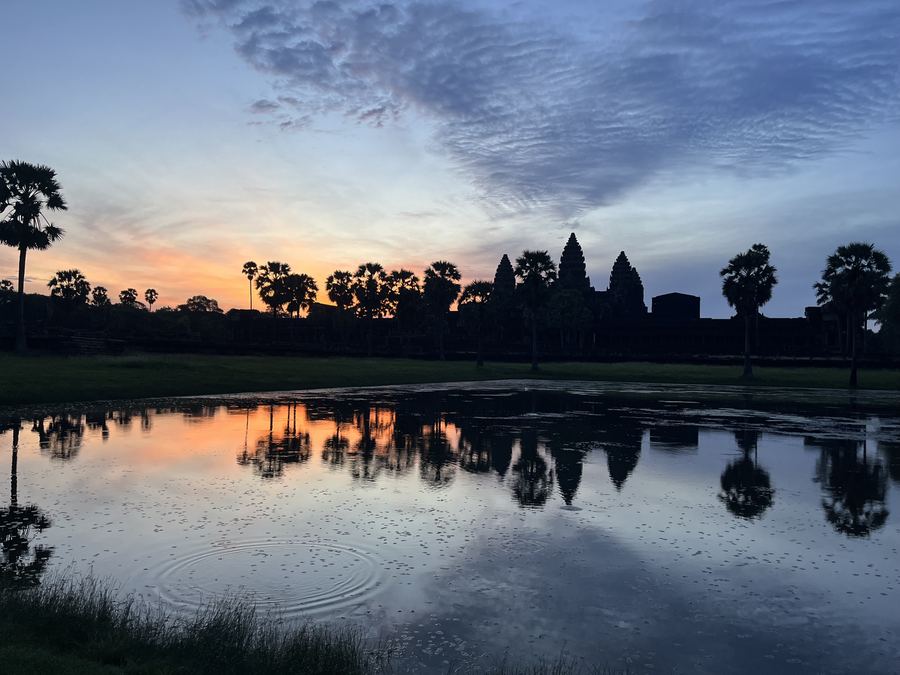 Angkor Wat silhouetted beyond a reflecting pool at first light