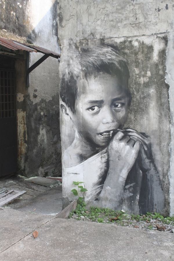 A large monochrome mural of a child painted on a peeling wall
