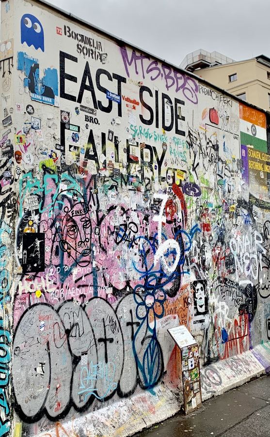 Layered graffiti and stickers covering the East Side Gallery wall