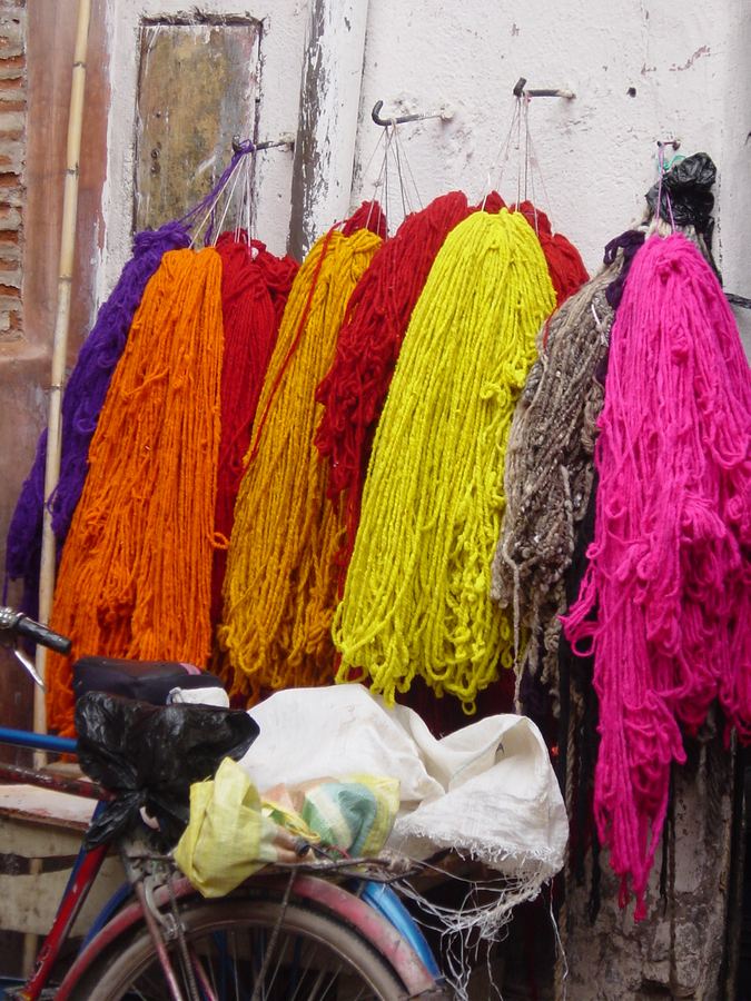 Skeins of dyed yarn hanging above a bicycle at a market stall