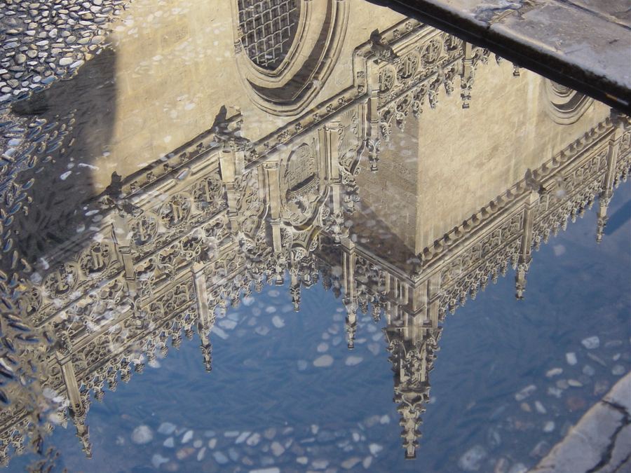A carved stone facade reflected in standing water