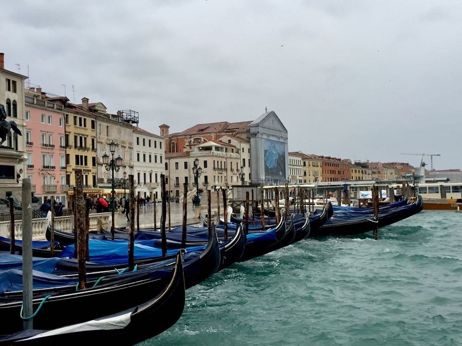 Gondolas moored along a Venetian waterfront under an overcast sky