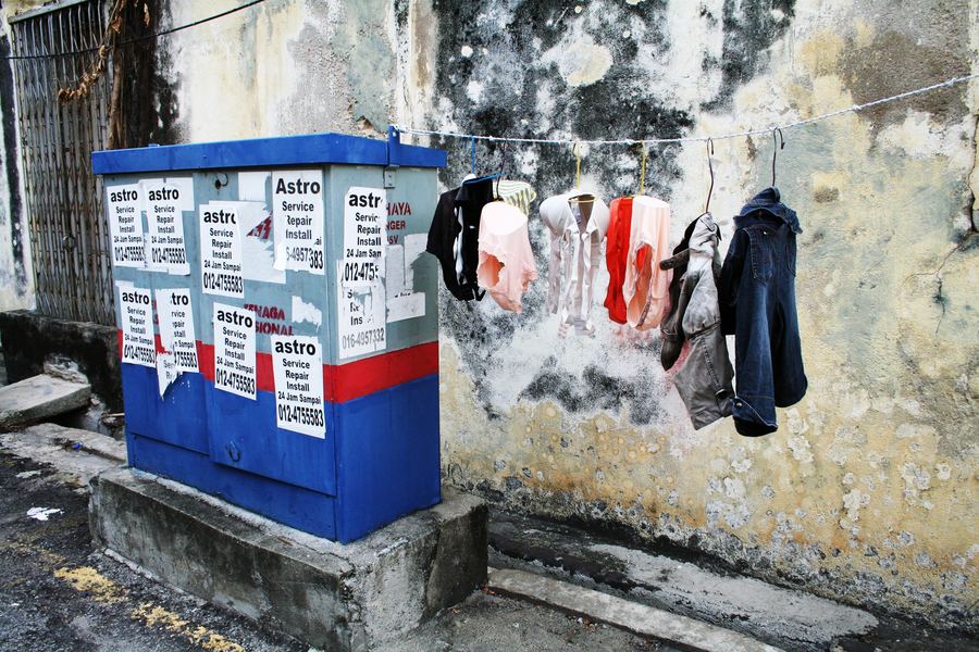 Laundry strung above utility boxes on a peeling wall