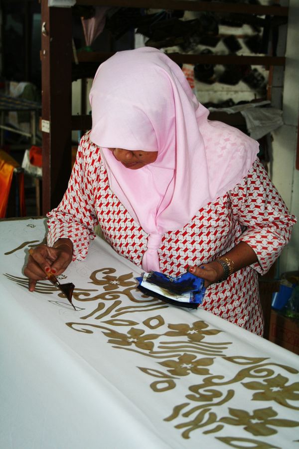 A woman drawing wax patterns onto batik cloth