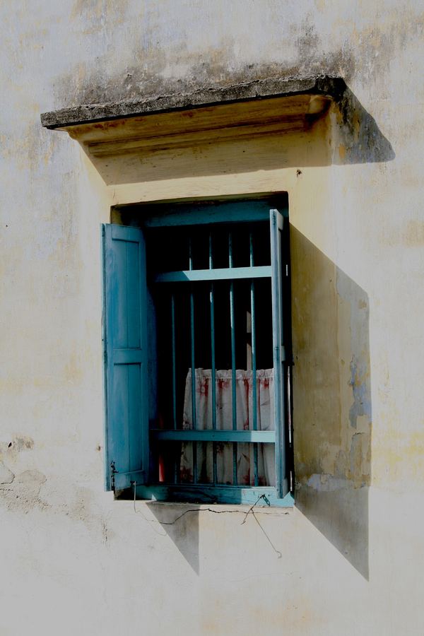 A turquoise shuttered window in a weathered wall