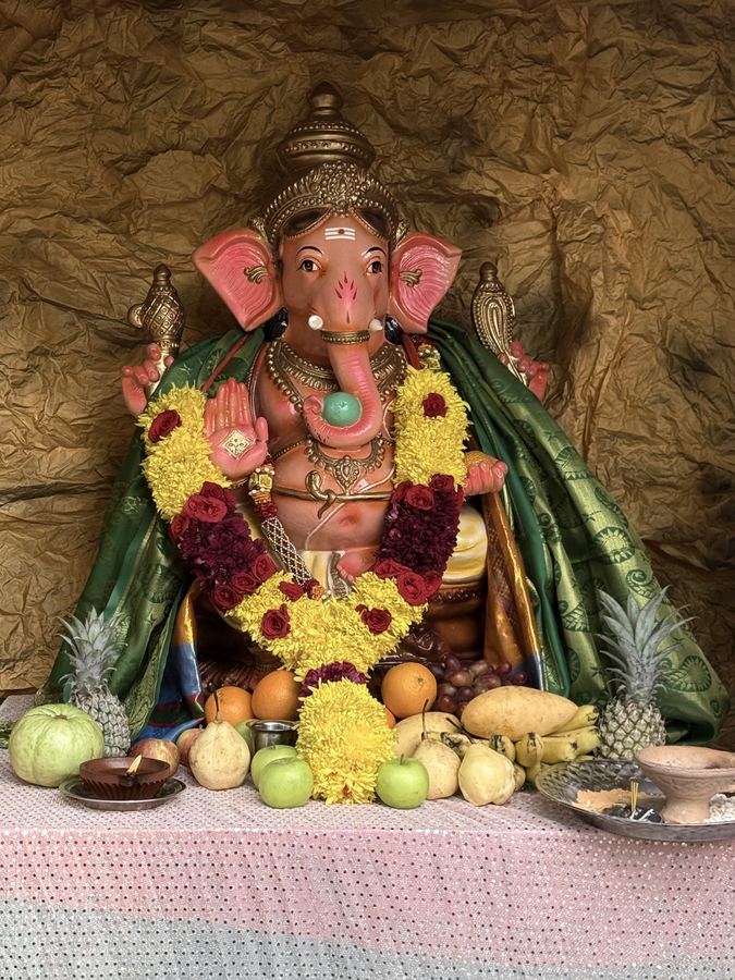 A Ganesha shrine dressed in garlands and surrounded by fruit offerings