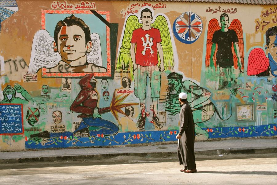 A figure walking past a painted memorial wall