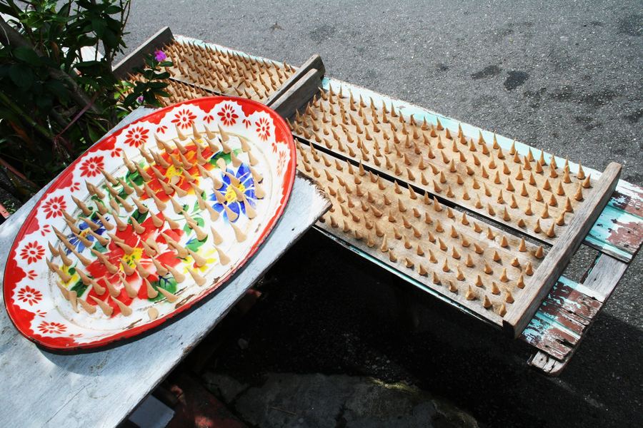 A dish of coloured rice-flour cones beside wooden moulding trays