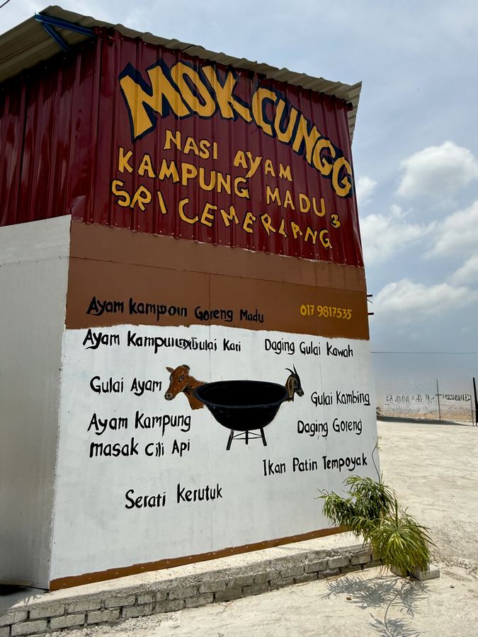 A hand-painted signboard for a village chicken stall above a beach