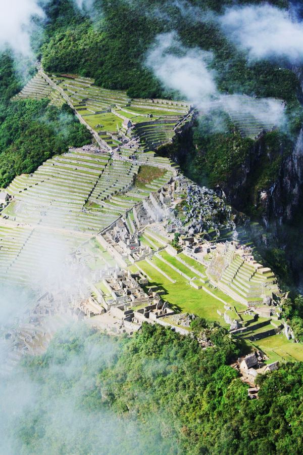 Terraced stone ruins in a mountain valley under cloud