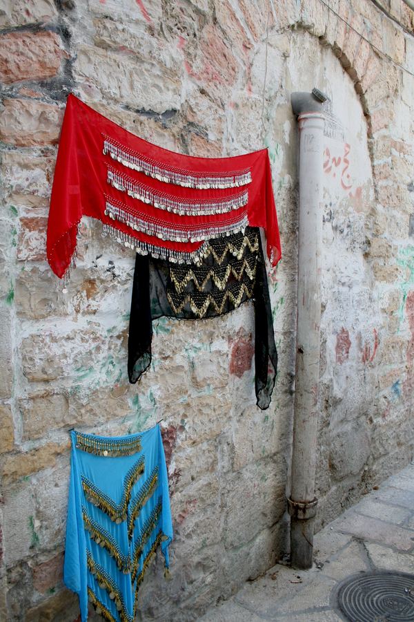 Beaded textiles hung against a stone wall