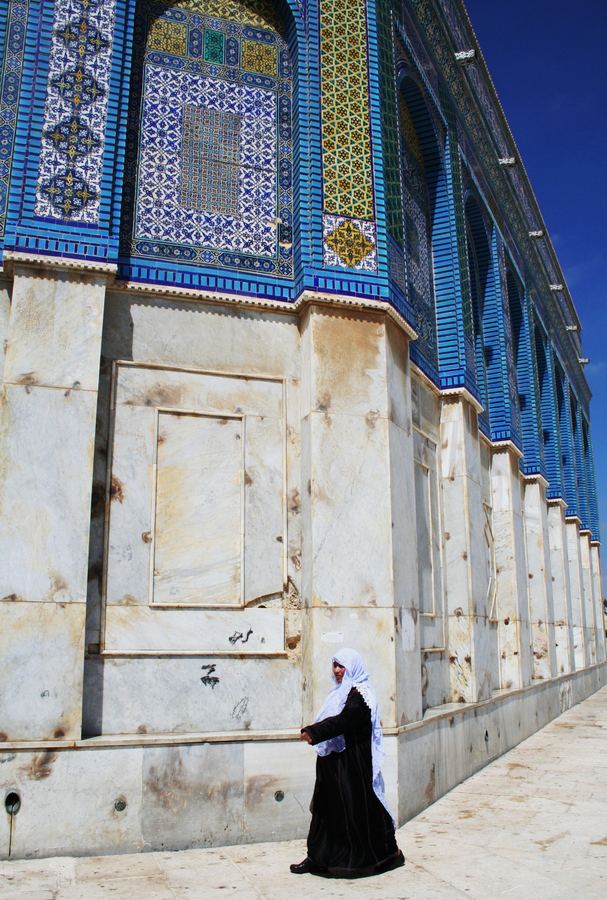 A woman walking beside a tiled facade