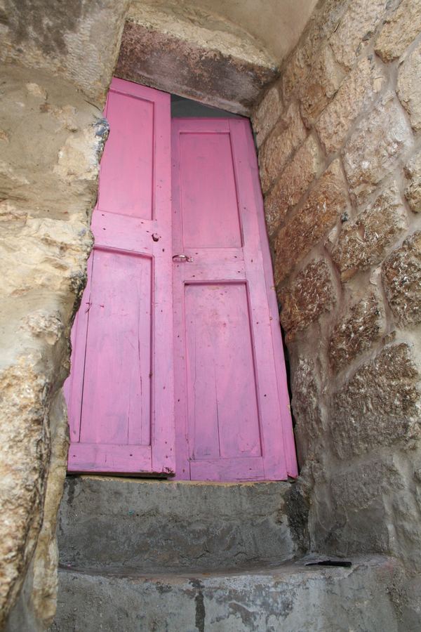 A bright pink door set into a rough stone doorway