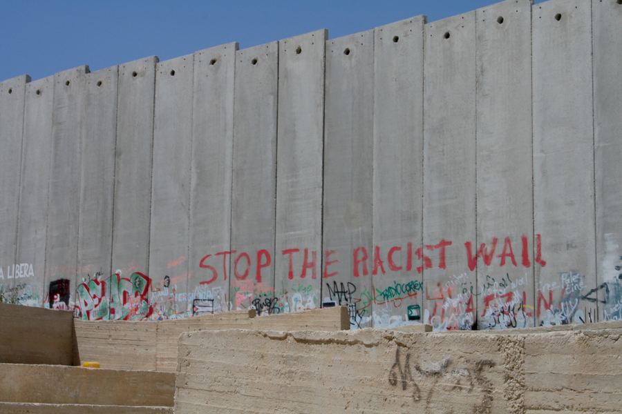 &ldquo;Stop the racist wall&rdquo; painted across a concrete separation barrier