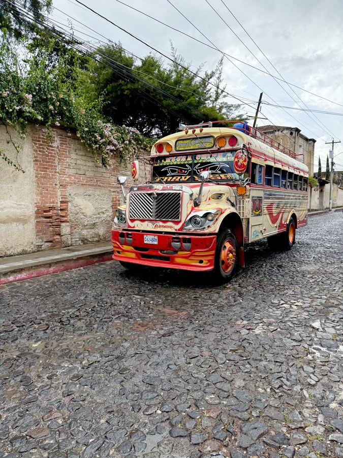 A brightly painted bus on a narrow cobbled street