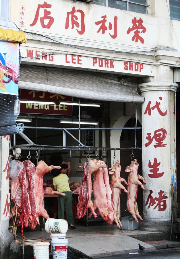 A butcher shop storefront with hanging carcasses and painted signage