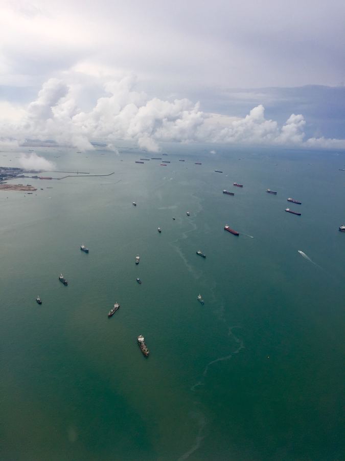 Cargo ships scattered across a green sea, seen from above