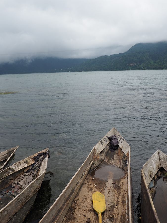 Wooden canoes drawn up on a lake shore under low cloud